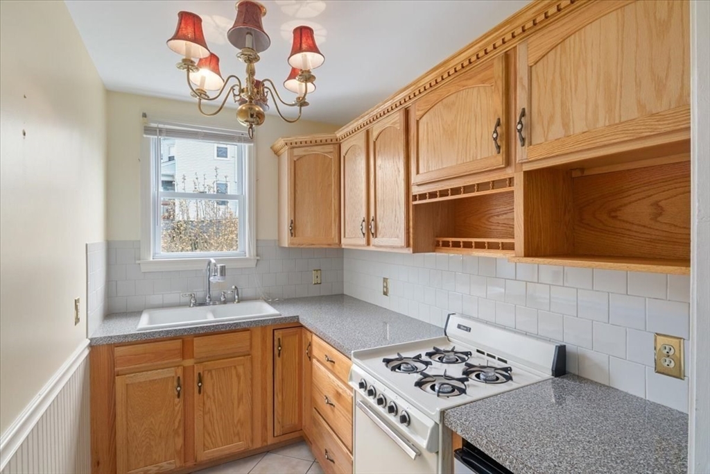 128 Diman Street Fall River, MA 02721 - Photo 9 of 42 a kitchen with stainless steel appliances granite countertop a sink dishwasher a stove a microwave oven with cabinets and wooden floor