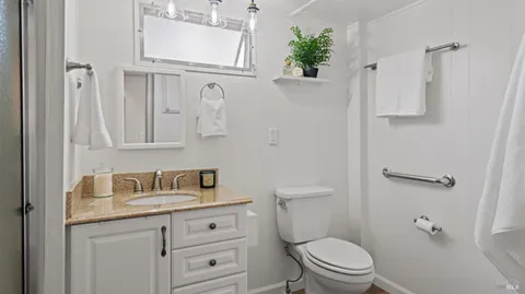 a bathroom with a granite countertop toilet sink and mirror
