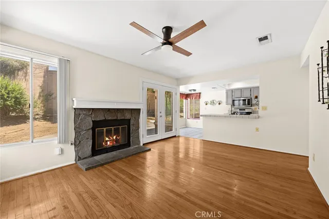 a view of a livingroom with a fireplace a ceiling fan and windows