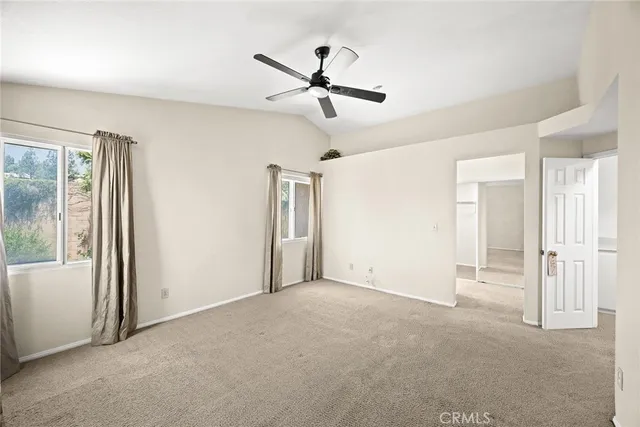 a view of a livingroom with a ceiling fan & windows