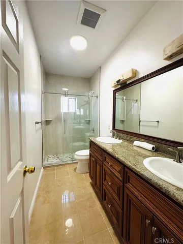 a spacious bathroom with a granite countertop sink a toilet a mirror and shower