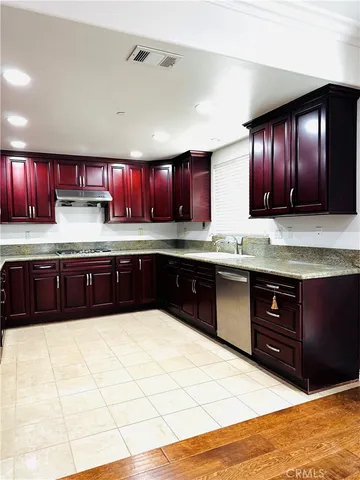 a large kitchen with stainless steel appliances granite countertop wooden cabinets a sink and dishwasher