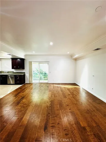 an empty room with wooden floor and stainless steel appliances