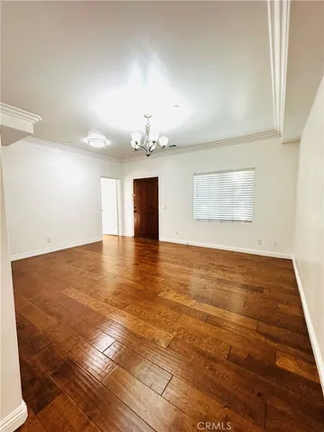 an empty room with wooden floor chandelier and windows