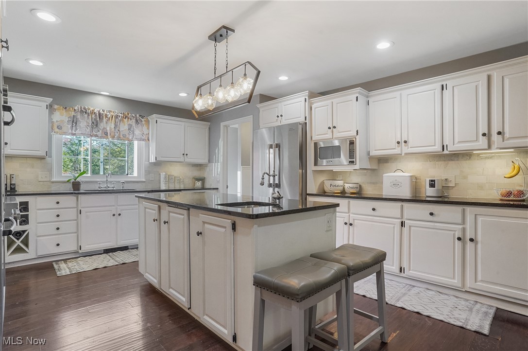 2070 Ridgewood Road Akron, OH 44313 - Photo 18 of 48 Kitchen featuring white cabinetry, decorative light fixtures, appliances with stainless steel finishes, and a center island