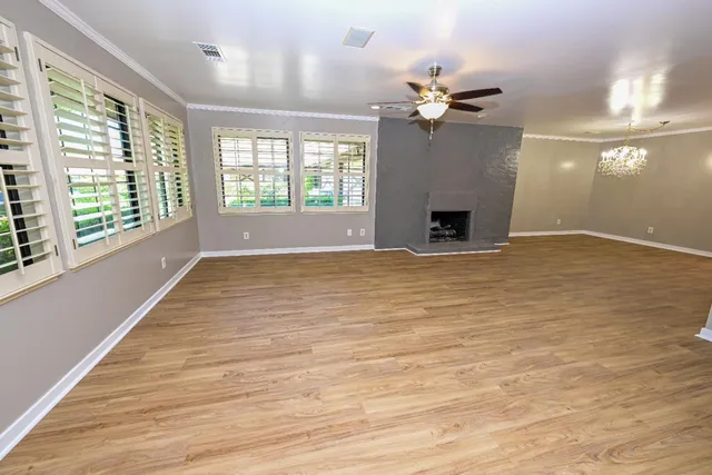 a view of a livingroom with a fireplace a ceiling fan and windows