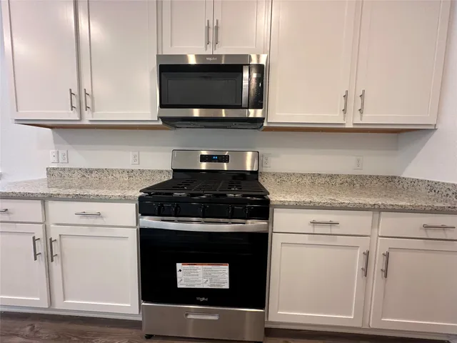 a kitchen with stainless steel appliances granite countertop white cabinets a sink and dishwasher