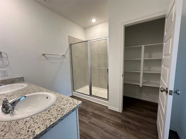 a bathroom with a granite countertop sink a mirror and shower