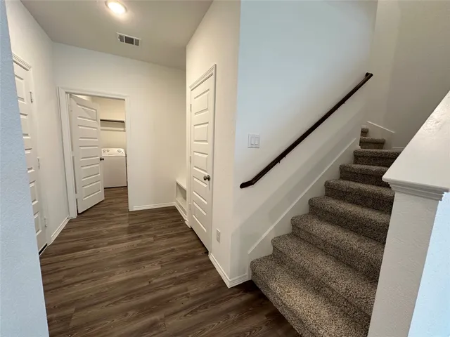 a view of a hallway with wooden floor and staircase