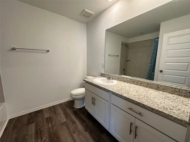 a bathroom with a granite countertop sink and a toilet