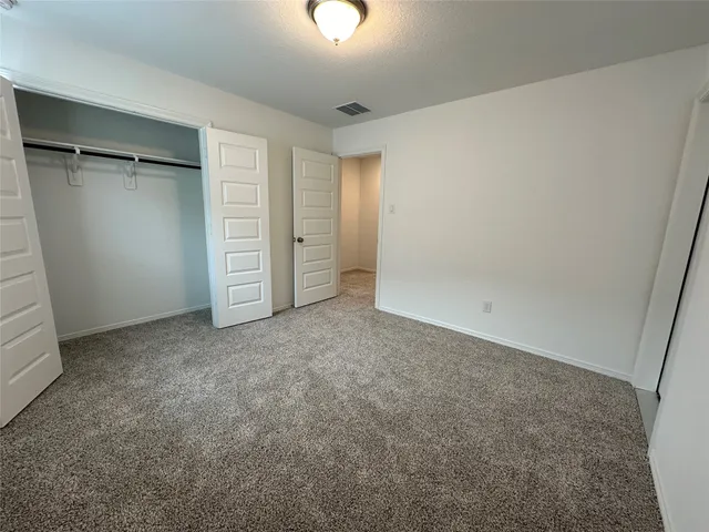 an empty room with closet and windows