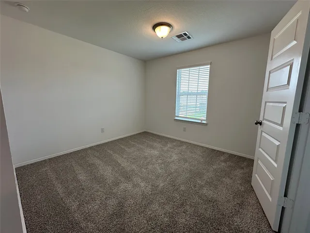 a view of an empty room with a window and fireplace
