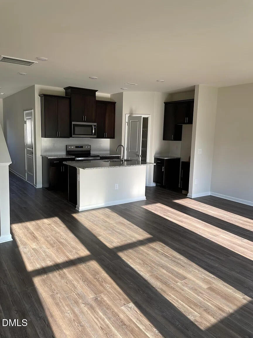 930 Field Ivy Drive Fuquay-Varina, NC 27526 - Photo 7 of 29 a kitchen with stainless steel appliances kitchen island granite countertop a refrigerator stove microwave and sink