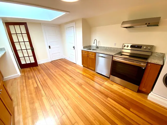 a kitchen with a sink appliances wooden floor and a window