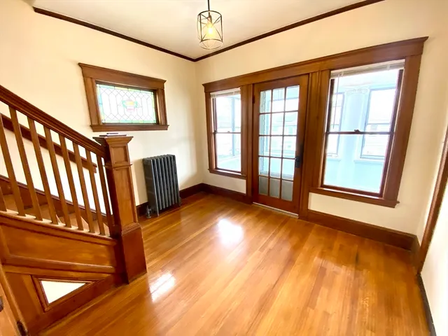 a view of an empty room with wooden floor and windows