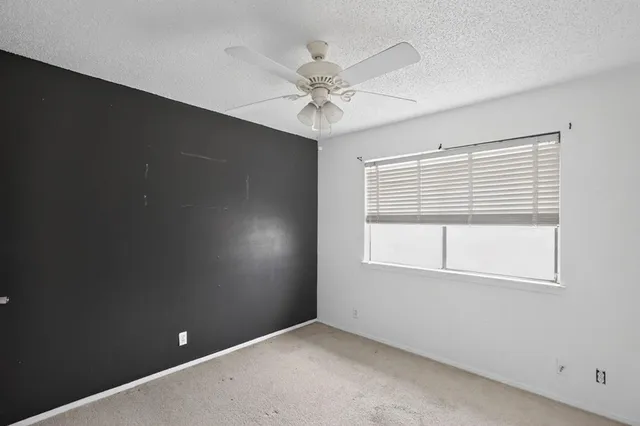 an empty room with a ceiling fan and a window