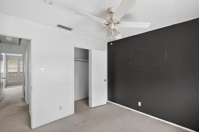 an empty room with windows and ceiling fan