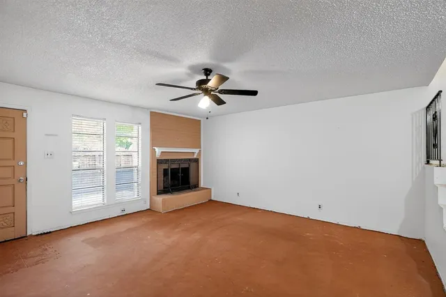 a view of a room with a ceiling fan fireplace and windows