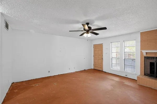 a view of an empty room with a fireplace and a window