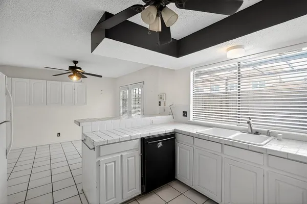 a kitchen with a sink dishwasher and white cabinets with wooden floor