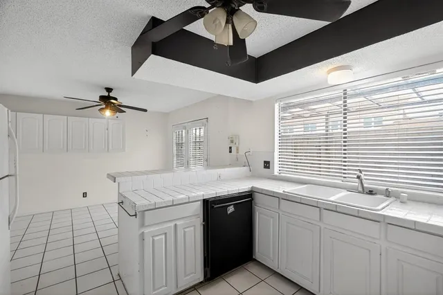 a kitchen with a sink dishwasher and white cabinets with wooden floor