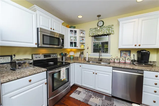 a kitchen with stainless steel appliances granite countertop a sink a stove and cabinets