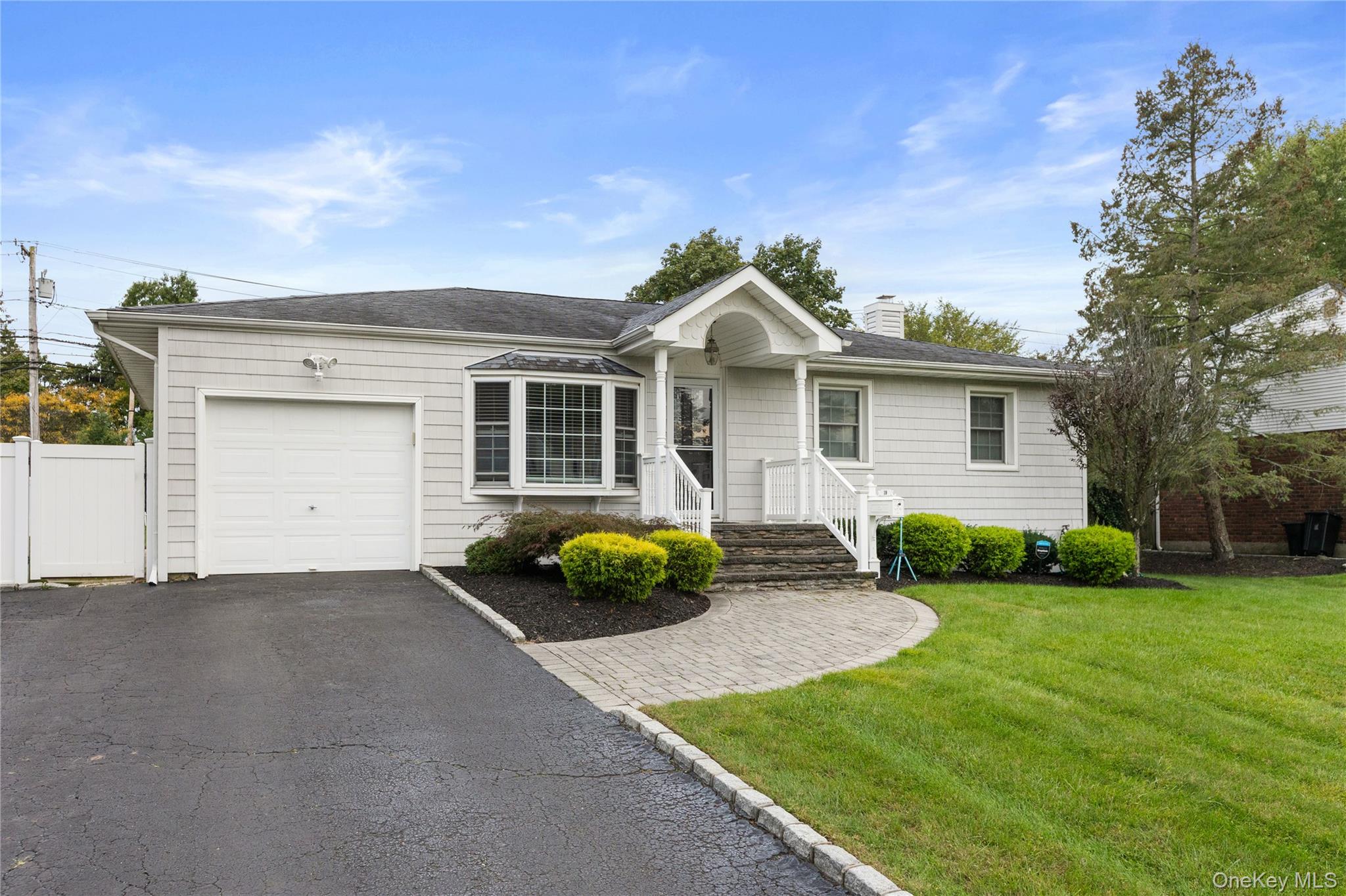 Ranch-style home with a front yard, asphalt driveway, a chimney, and an attached garage
