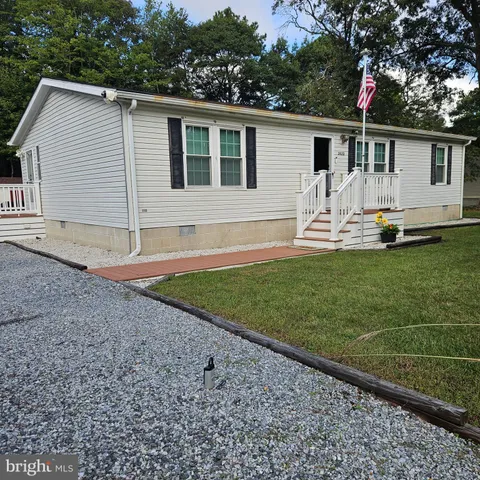 a view of a white house with a yard and wooden fence