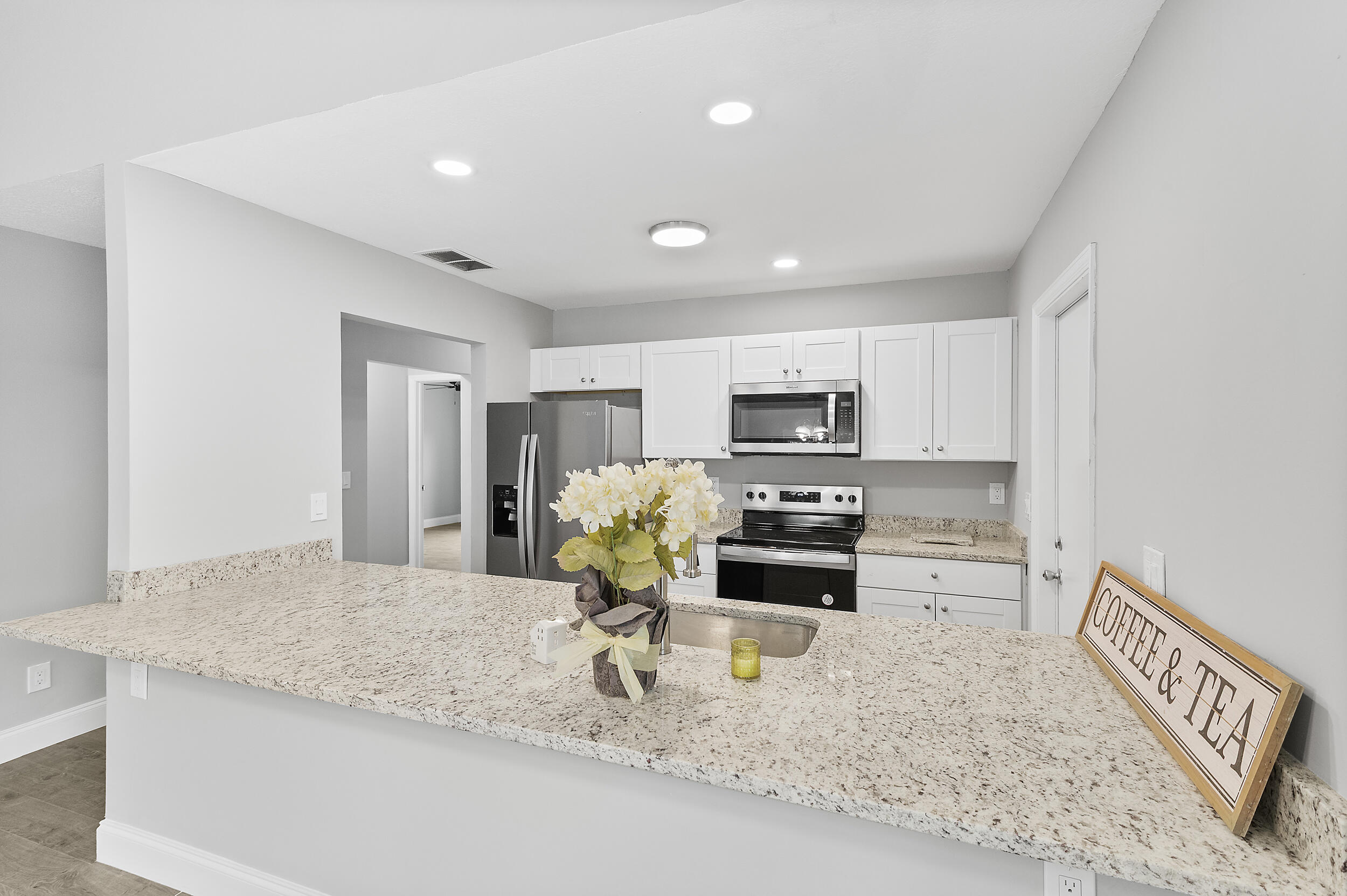 4777 Southeast Salvatori Road Stuart, FL 34997 - Photo 4 of 28 a kitchen with stainless steel appliances kitchen island granite countertop a sink refrigerator and microwave