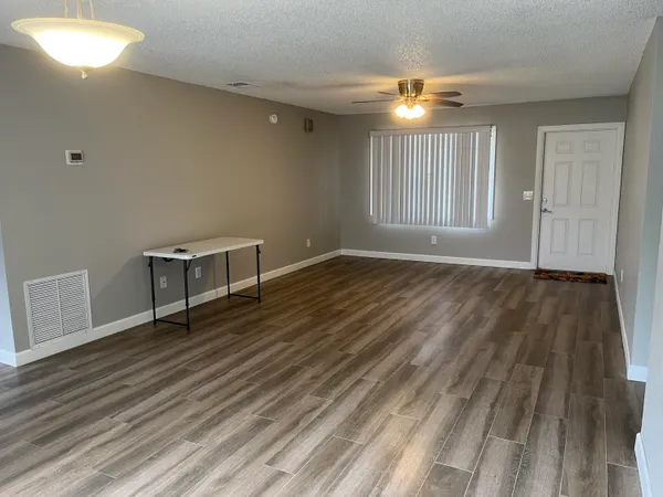 a view of an empty room with wooden floor and a window