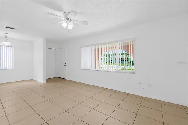 an empty room with windows and fan