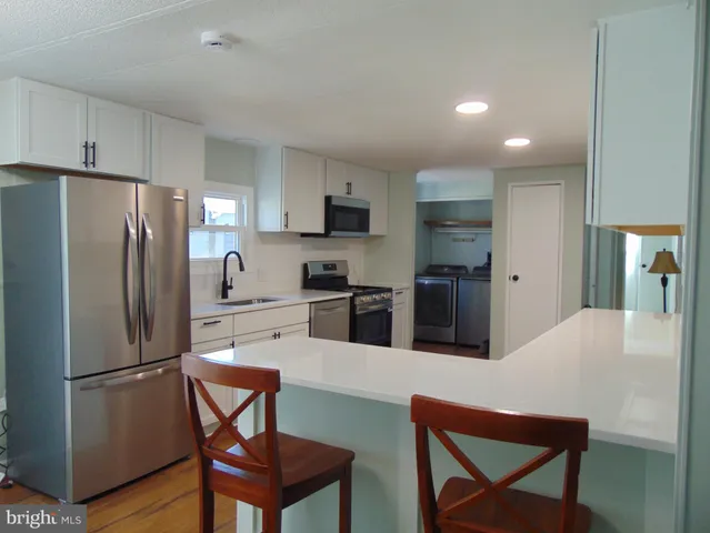 a kitchen with stainless steel appliances a refrigerator a stove a sink a dining table and chairs