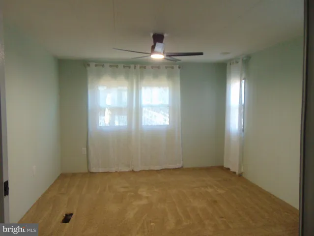 an empty room with chandelier fan and windows