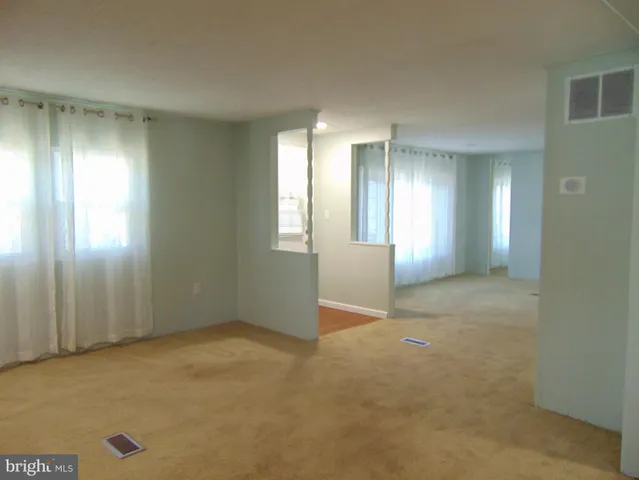 a view of an empty room with window and bathroom