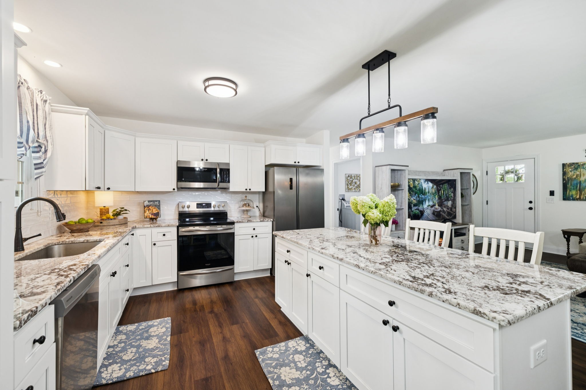 a large kitchen with a stove a sink dishwasher a refrigerator and white cabinets with wooden floor