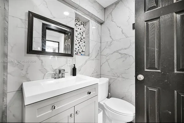 a bathroom with a toilet sink vanity and mirror