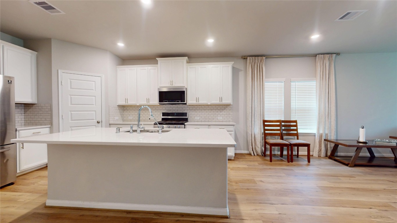 21606 Reserve Ranch Trail Richmond, TX 77407 - Photo 14 of 48 a large kitchen with kitchen island a stove a sink a dining table and chairs