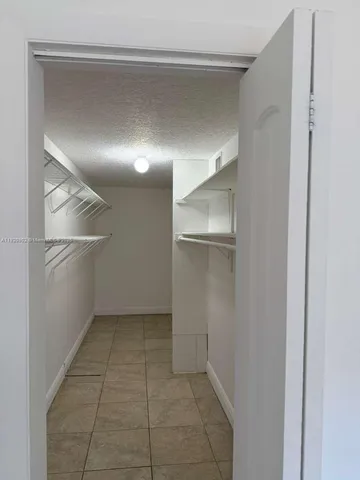 a view of an empty room with closet and windows