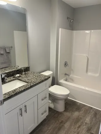 a bathroom with a granite countertop sink a toilet and a mirror