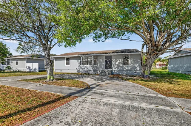 a view of a house with a yard and large tree