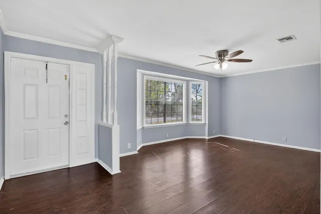 a view of an empty room with a window and wooden floor