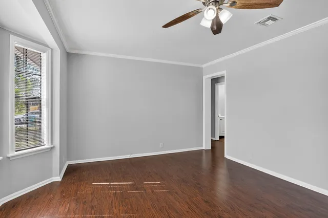 an empty room with wooden floor fan and windows