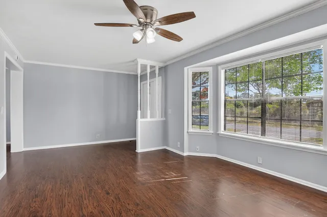 a view of an empty room with a window and wooden floor
