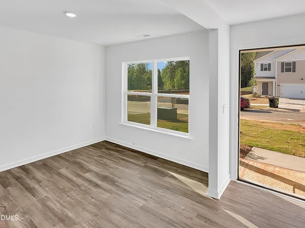 a view of an empty room with wooden floor and windows