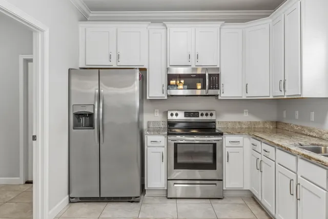 a kitchen with granite countertop white cabinets white stainless steel appliances with a sink and dishwasher