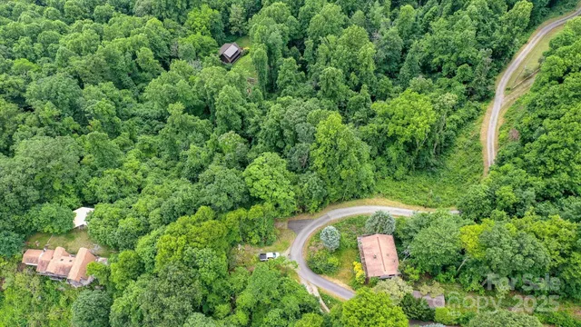 an aerial view of residential house with outdoor space and trees all around