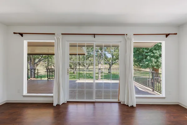 a view of empty room with wooden floor and floor to ceiling window
