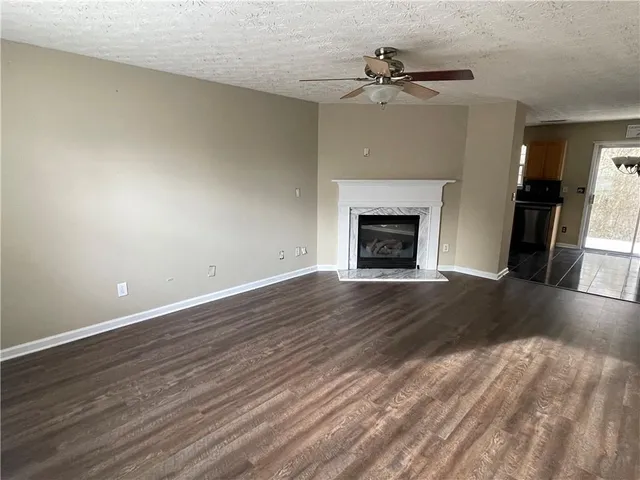 an empty room with wooden floor fireplace and windows
