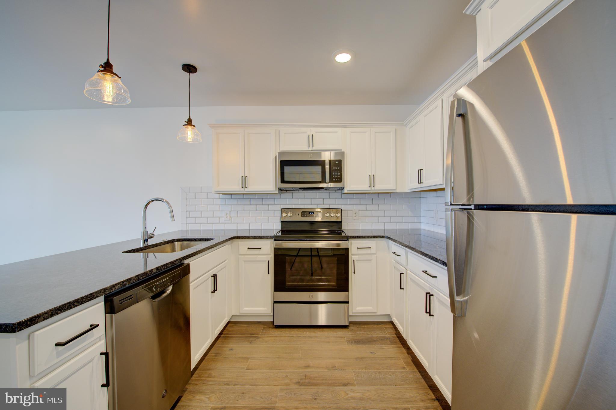6649 Ridge Avenue, Unit B201 Philadelphia, PA 19128 - Photo 2 of 12 a kitchen with granite countertop a sink stainless steel appliances and cabinets