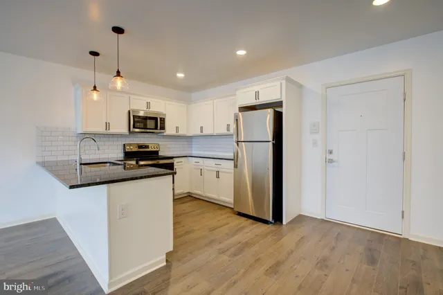 a kitchen with kitchen island a refrigerator a stove top oven a sink and dishwasher with wooden floor